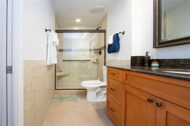 bathroom featuring a shower stall, vanity, tile patterned flooring, toilet, and tile walls