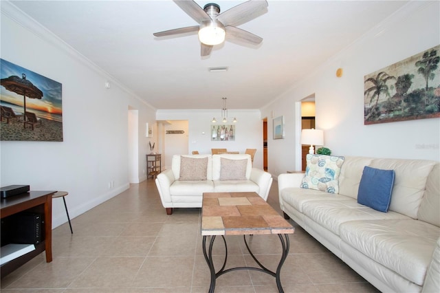 living area featuring ceiling fan with notable chandelier, ornamental molding, visible vents, light tile patterned flooring, and baseboards
