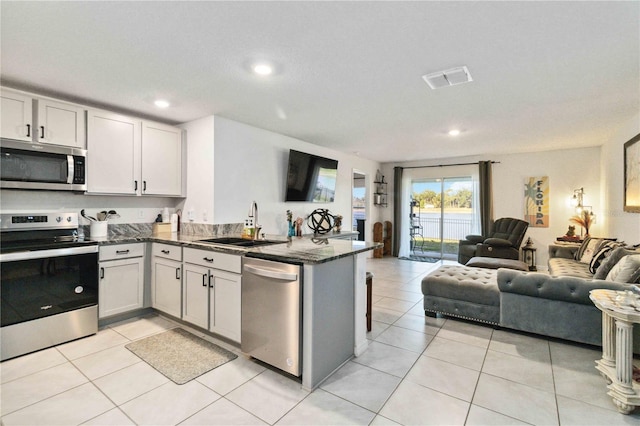 2812 Rock Sound St, Bradenton, FL 34208 - kitchen with stainless steel appliances, open floor plan, a sink, a peninsula, and dark stone counters