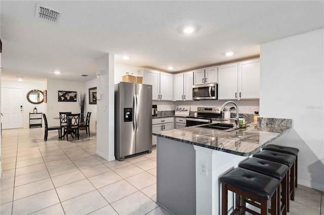 2812 Rock Sound St, Bradenton, FL 34208 - kitchen featuring stainless steel appliances, a sink, dark stone countertops, a peninsula, and a kitchen breakfast bar