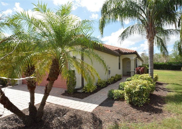 view of side of property with driveway, a tile roof, and stucco siding
