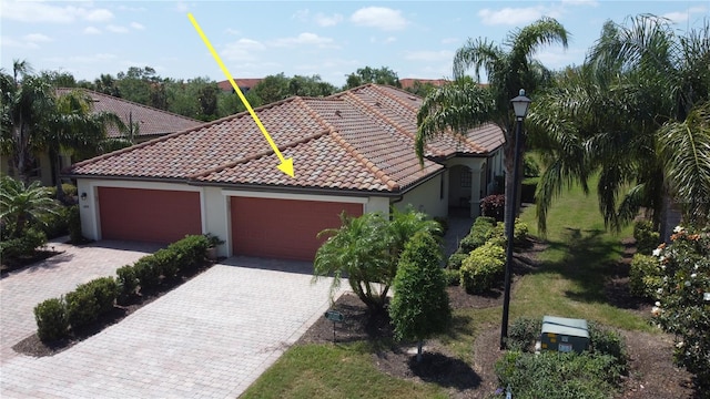 view of front of home featuring decorative driveway, a garage, stucco siding, and a tile roof
