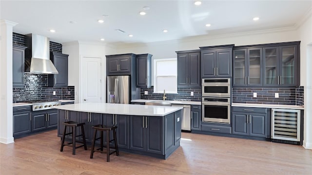 15722 San Lazzaro Ave, Lakewood Ranch, FL 34211 - kitchen featuring a breakfast bar, wall chimney range hood, a kitchen island, stainless steel appliances, and beverage cooler