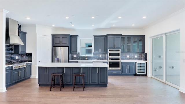 15722 San Lazzaro Ave, Lakewood Ranch, FL 34211 - kitchen featuring a center island, wall chimney range hood, light countertops, appliances with stainless steel finishes, and beverage cooler