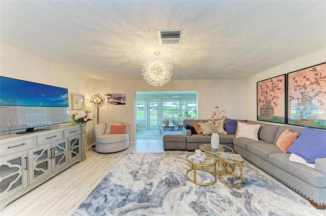 1622 Stafford Ln Unit 1205, Sarasota, FL 34232 - living room featuring an inviting chandelier, a textured ceiling, visible vents, and light wood-type flooring