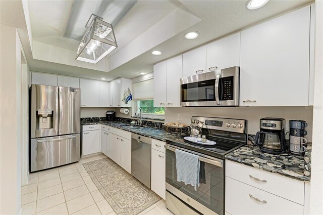 1622 Stafford Ln Unit 1205, Sarasota, FL 34232 - kitchen featuring dark stone countertops, light tile patterned floors, a sink, appliances with stainless steel finishes, and white cabinetry