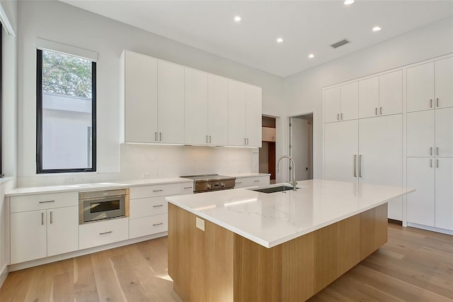 7200 Chameleon Way, Sarasota, FL 34241 - kitchen with light wood finished floors, recessed lighting, an island with sink, white cabinets, and light stone countertops