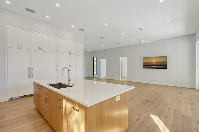 7200 Chameleon Way, Sarasota, FL 34241 - kitchen with light wood-type flooring, a kitchen island with sink, modern cabinets, a ceiling fan, and light stone countertops