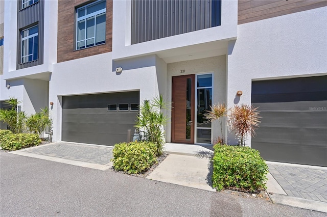221 Cosmopolitan Ct, Sarasota, FL 34236 - doorway to property with a garage, stucco siding, and decorative driveway