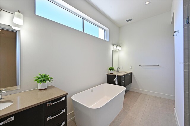 221 Cosmopolitan Ct, Sarasota, FL 34236 - bathroom featuring two vanities, baseboards, a freestanding tub, and a sink