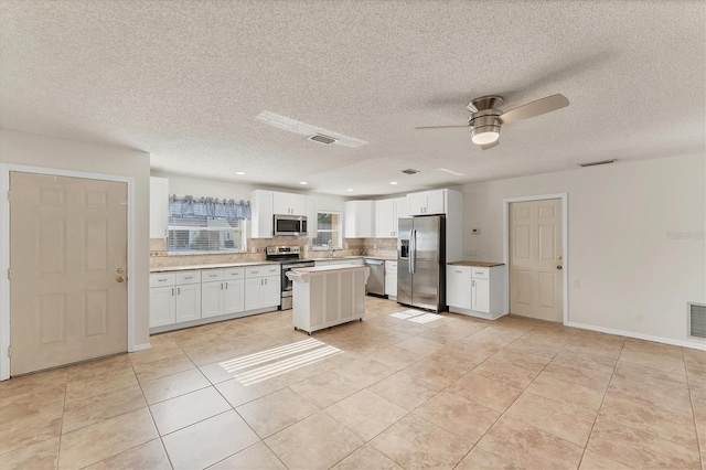 2151 Upton Ave, Sarasota, FL 34232 - kitchen with ceiling fan, white cabinetry, backsplash, light tile patterned floors, and stainless steel appliances