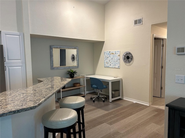 4166 Central Sarasota Pkwy Unit 535, Sarasota, FL 34238 - interior space with visible vents, baseboards, a breakfast bar, wood finished floors, and stone counters