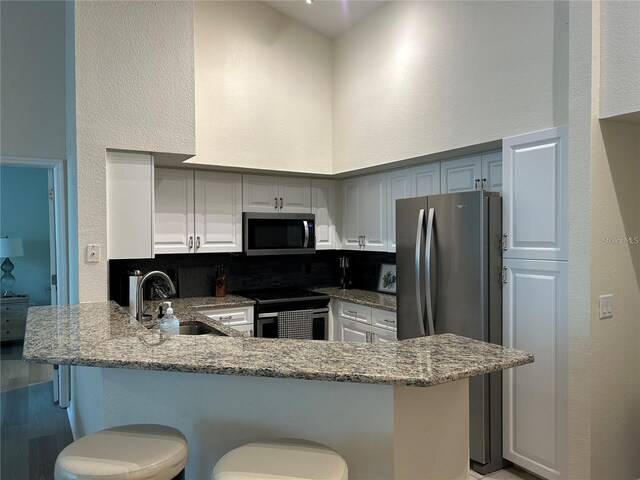 4166 Central Sarasota Pkwy Unit 535, Sarasota, FL 34238 - kitchen featuring a sink, appliances with stainless steel finishes, a kitchen bar, a peninsula, and light stone counters