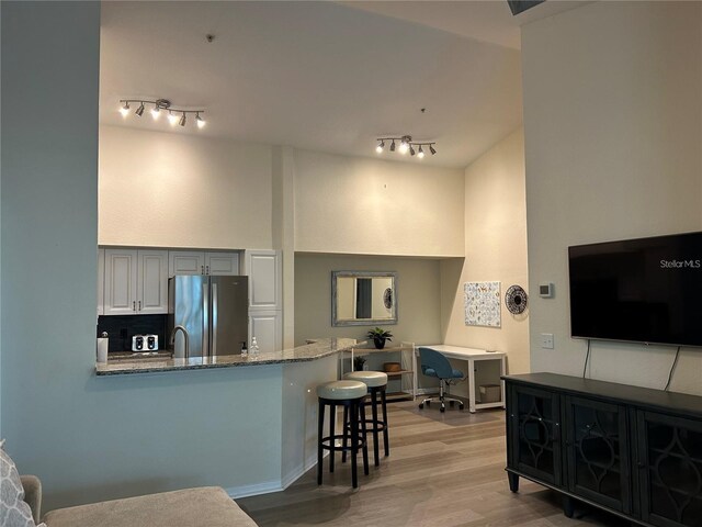 4166 Central Sarasota Pkwy Unit 535, Sarasota, FL 34238 - kitchen with freestanding refrigerator, light wood-type flooring, a peninsula, stone counters, and a breakfast bar