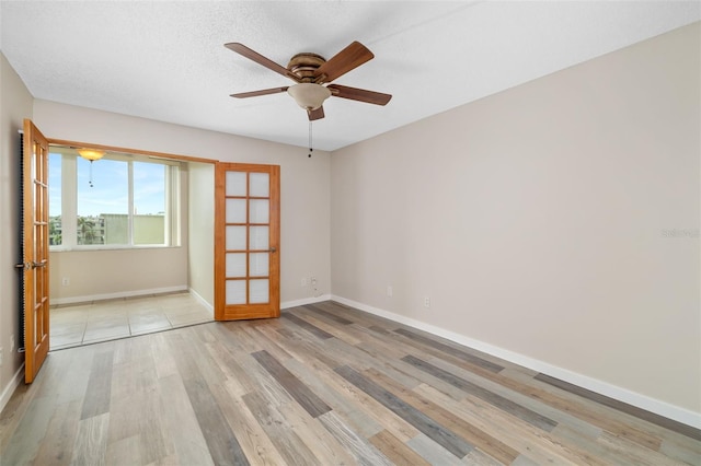 4885 1st St NE Unit 308, Saint Petersburg, FL 33703 - empty room featuring light wood-style flooring, a textured ceiling, a ceiling fan, french doors, and baseboards