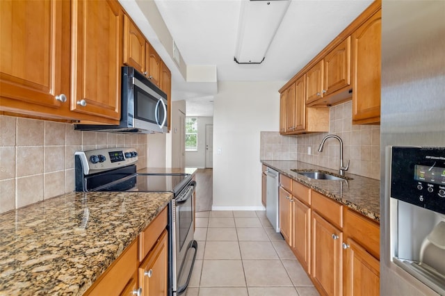 4885 1st St NE Unit 308, Saint Petersburg, FL 33703 - kitchen featuring dark stone countertops, light tile patterned flooring, a sink, stainless steel appliances, and brown cabinets