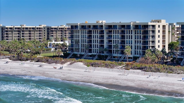 view of building exterior with a water view and a beach view