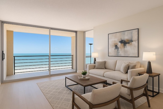 living room with a water view, plenty of natural light, wood finished floors, and expansive windows