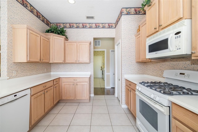 244 Dove Trl, Bradenton, FL 34212 - kitchen with white appliances, wallpapered walls, light brown cabinetry, light countertops, and light tile patterned flooring