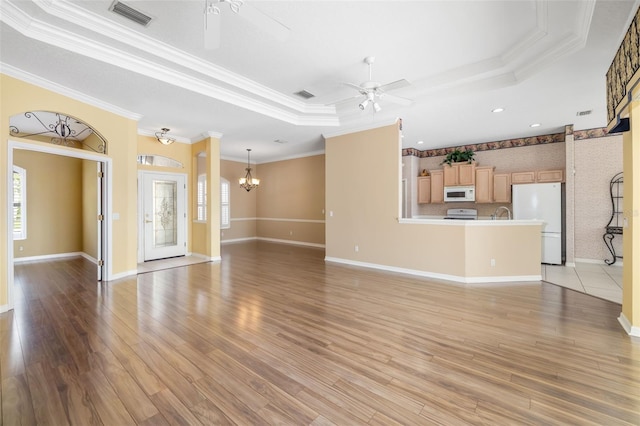 244 Dove Trl, Bradenton, FL 34212 - unfurnished living room featuring a raised ceiling, a ceiling fan, ornamental molding, plenty of natural light, and light wood-style flooring