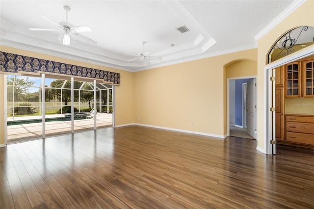 244 Dove Trl, Bradenton, FL 34212 - empty room with arched walkways, ornamental molding, ceiling fan, a raised ceiling, and dark wood-style flooring