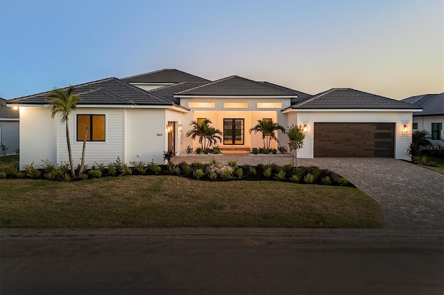 1613 4th St E, Palmetto, FL 34221 - prairie-style house featuring an attached garage, decorative driveway, a lawn, and stucco siding