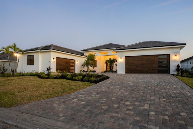 1613 4th St E, Palmetto, FL 34221 - view of front facade with a garage, decorative driveway, a front yard, and stucco siding