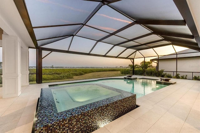 1613 4th St E, Palmetto, FL 34221 - pool at dusk with a pool with connected hot tub, a patio area, and glass enclosure