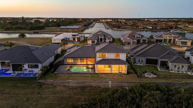 1613 4th St E, Palmetto, FL 34221 - back of house at dusk featuring a water view, a fenced backyard, a residential view, and an outdoor pool