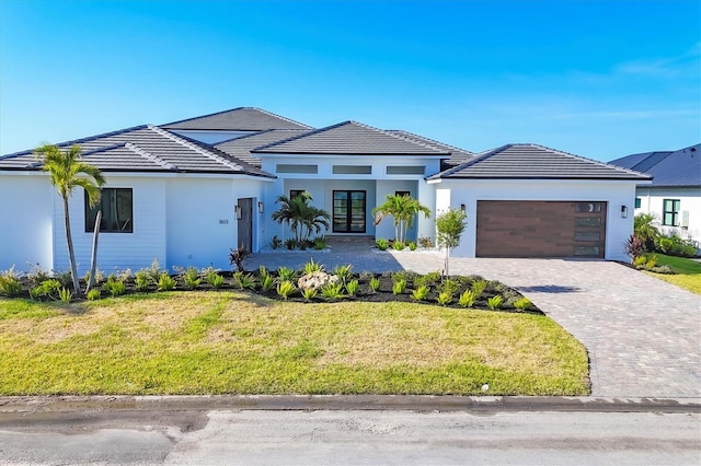 1613 4th St E, Palmetto, FL 34221 - view of front facade with french doors, an attached garage, and stucco siding