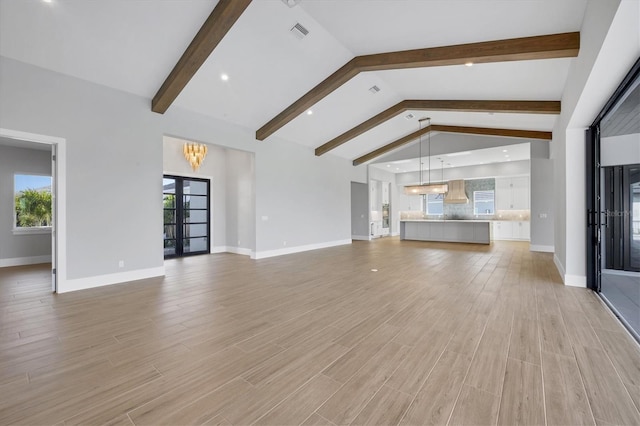 1613 4th St E, Palmetto, FL 34221 - unfurnished living room with beam ceiling, french doors, light wood-style floors, high vaulted ceiling, and baseboards