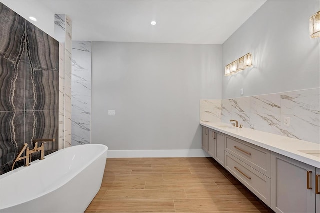 1613 4th St E, Palmetto, FL 34221 - full bath with a freestanding tub, double vanity, wood finished floors, baseboards, and recessed lighting