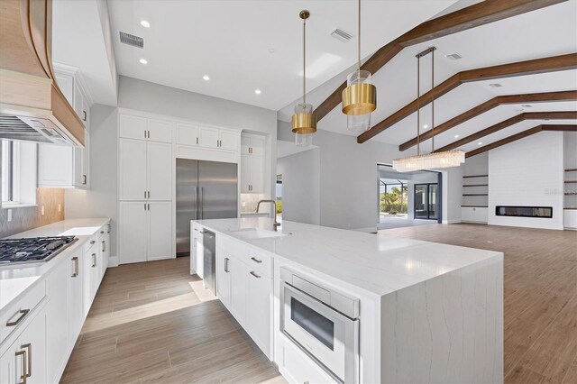 1613 4th St E, Palmetto, FL 34221 - kitchen featuring built in appliances, a sink, a large island, light stone counters, and hanging light fixtures