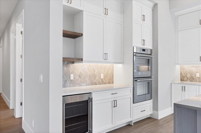 1613 4th St E, Palmetto, FL 34221 - kitchen with open shelves, wine cooler, double oven, baseboards, and light wood-style floors