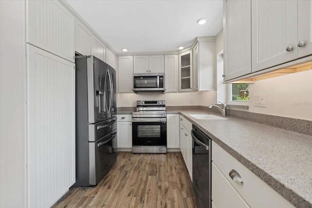 6718 68th Ave E, Bradenton, FL 34203 - kitchen with glass insert cabinets, light wood-style flooring, light countertops, appliances with stainless steel finishes, and a sink