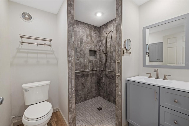 6718 68th Ave E, Bradenton, FL 34203 - full bathroom featuring vanity, baseboards, toilet, a tile shower, and wood finished floors