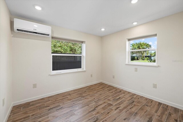 6718 68th Ave E, Bradenton, FL 34203 - empty room with wood finished floors, baseboards, an AC wall unit, and recessed lighting