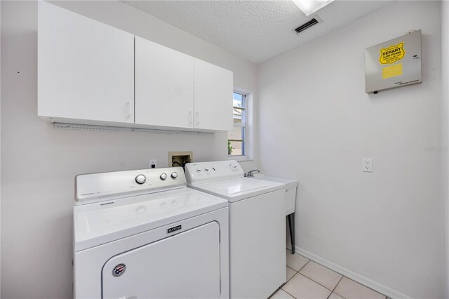 8824 Havenridge Dr, Sarasota, FL 34238 - clothes washing area with light tile patterned floors, baseboards, a textured ceiling, cabinet space, and washer and clothes dryer