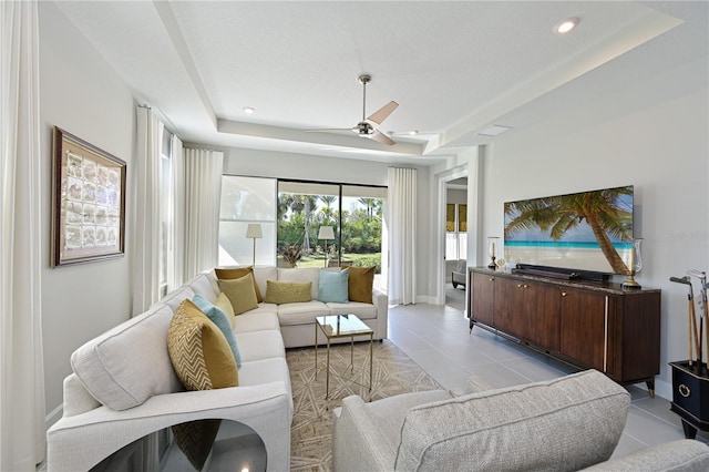 living room with light tile patterned floors, baseboards, a raised ceiling, ceiling fan, and recessed lighting