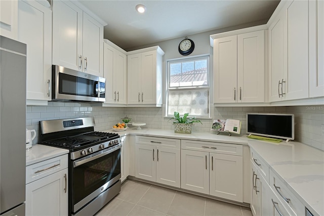 kitchen featuring tasteful backsplash, light stone counters, light tile patterned floors, white cabinetry, and stainless steel appliances