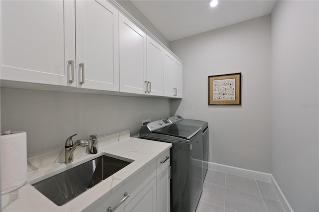 laundry room with baseboards, tile patterned floors, washer and clothes dryer, cabinet space, and a sink