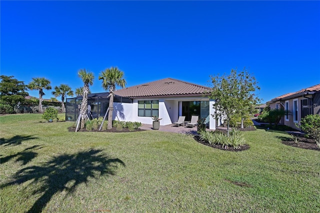 rear view of house with a tiled roof, a yard, and stucco siding