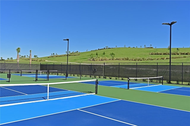 view of tennis court featuring community basketball court and fence