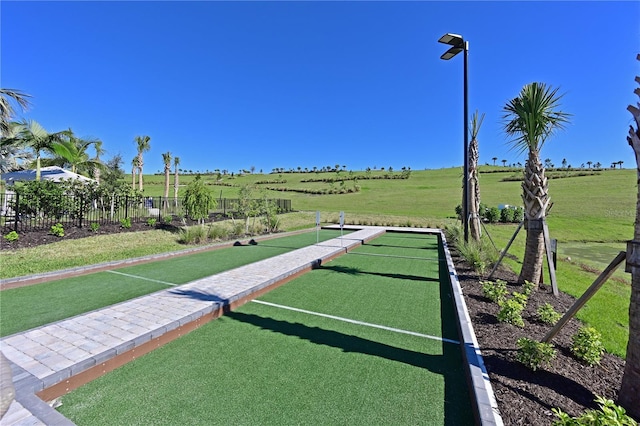 view of home's community featuring a rural view, fence, and a lawn