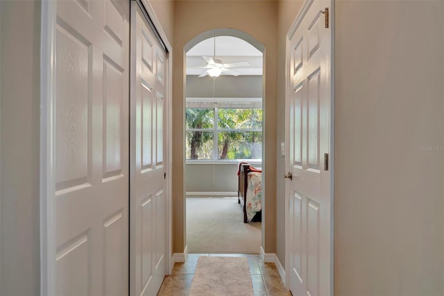 5009 Lake Overlook Ave, Bradenton, FL 34208 - hallway featuring light tile patterned floors, baseboards, arched walkways, and light colored carpet