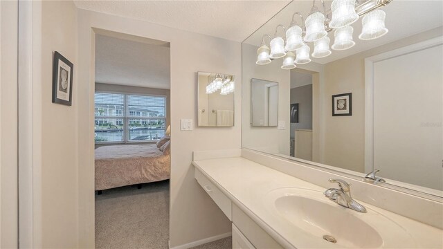 4350 Chatham Dr Unit E-105, Longboat Key, FL 34228 - bathroom with a chandelier, ensuite bathroom, vanity, baseboards, and a textured ceiling