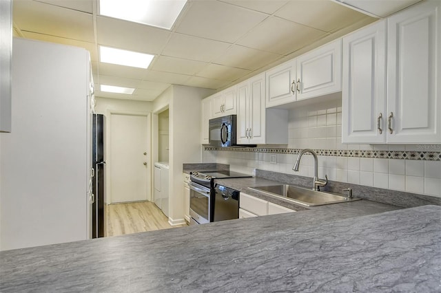 7173 W Country Club Dr N Unit 141, Sarasota, FL 34243 - kitchen with backsplash, white cabinets, black appliances, washer and dryer, and a sink