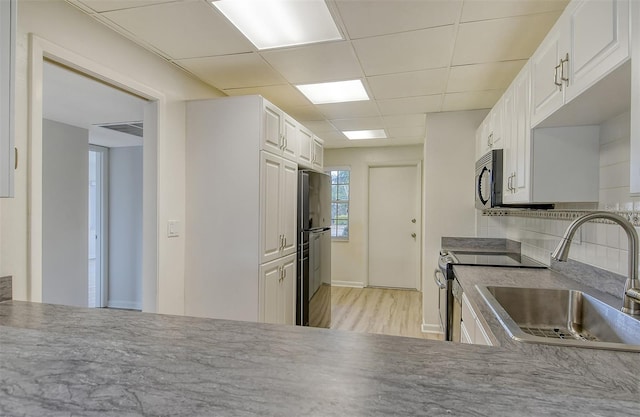 7173 W Country Club Dr N Unit 141, Sarasota, FL 34243 - kitchen featuring white cabinets, a sink, a paneled ceiling, black appliances, and light wood-style flooring