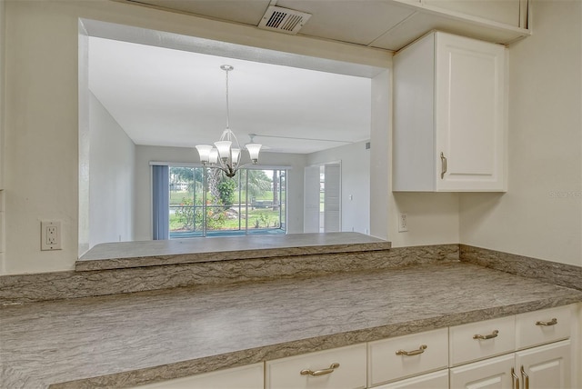 7173 W Country Club Dr N Unit 141, Sarasota, FL 34243 - interior space featuring white cabinetry, visible vents, a chandelier, light countertops, and hanging light fixtures