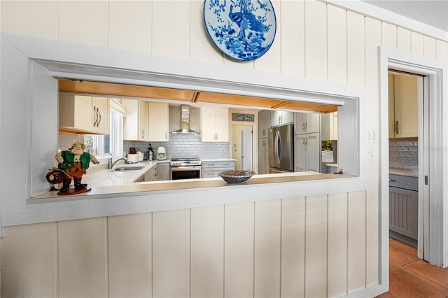 8592 Hidden Lagoon Rd, Sarasota, FL 34242 - kitchen featuring stainless steel appliances, wall chimney range hood, backsplash, light countertops, and light wood-style floors